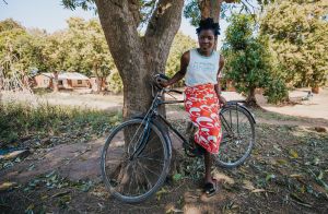 Teenage African girl standing with bicycle