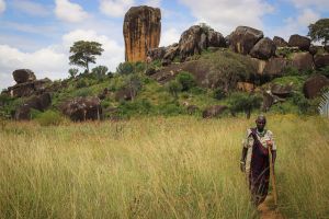 Field with rocks and African woman walking