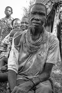 Black and white image of elderly African woman with beads around neck