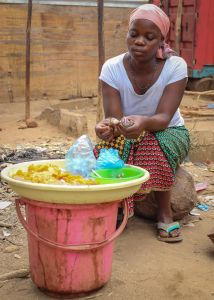 African woman sitting and handling food