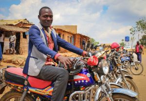 African man on motorcycle with village backdrop