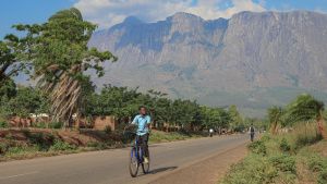 African boy on bicycle with mountains in background