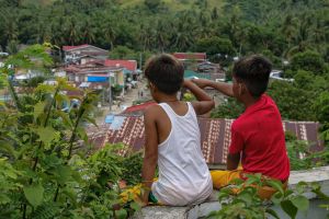Two young Asian boys looking out at village below