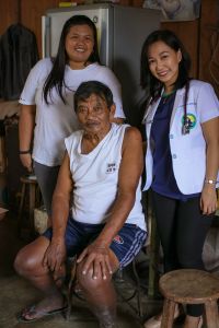 Asian health workers standing with old man sitting