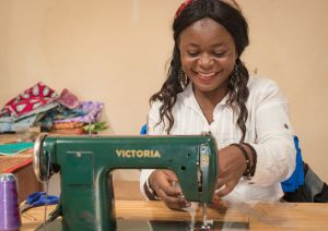African woman smiling with sewing machine