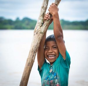 Young Latin American boy hanging off wooden pole