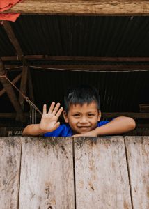 Little Latin American boy waving from house